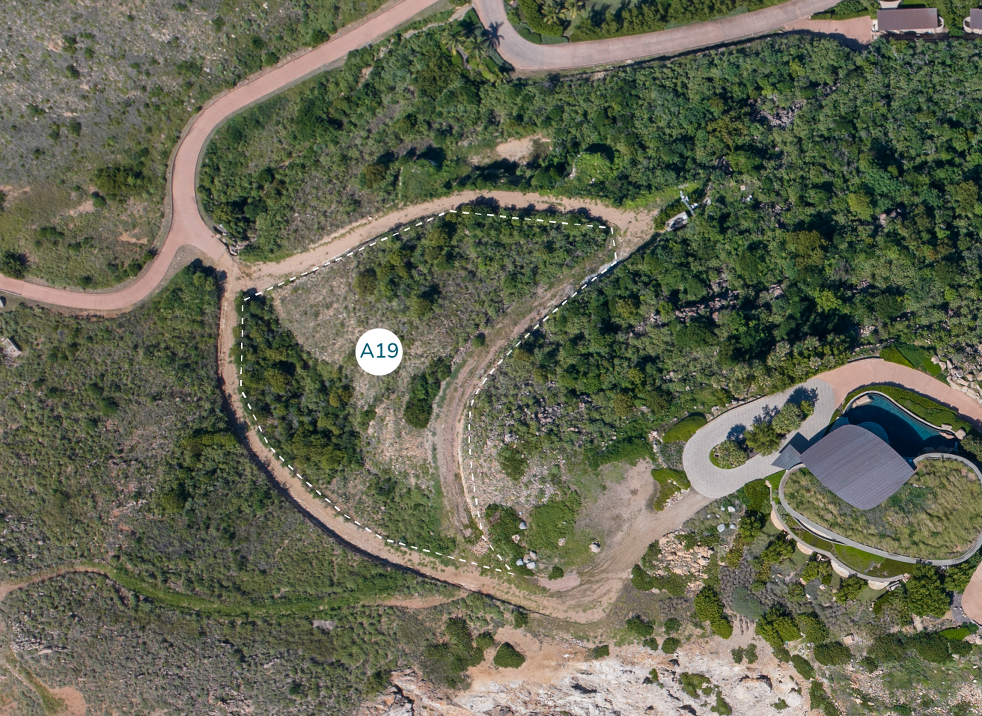 Aerial view of a park area showing a curved pathway labeled "Homesite A19" amidst greenery. There's a circular structure with a black roof at the bottom right, roads surrounding the area, and forested regions throughout. Rocky terrain can be seen at the bottom near Atlantic Ridge.