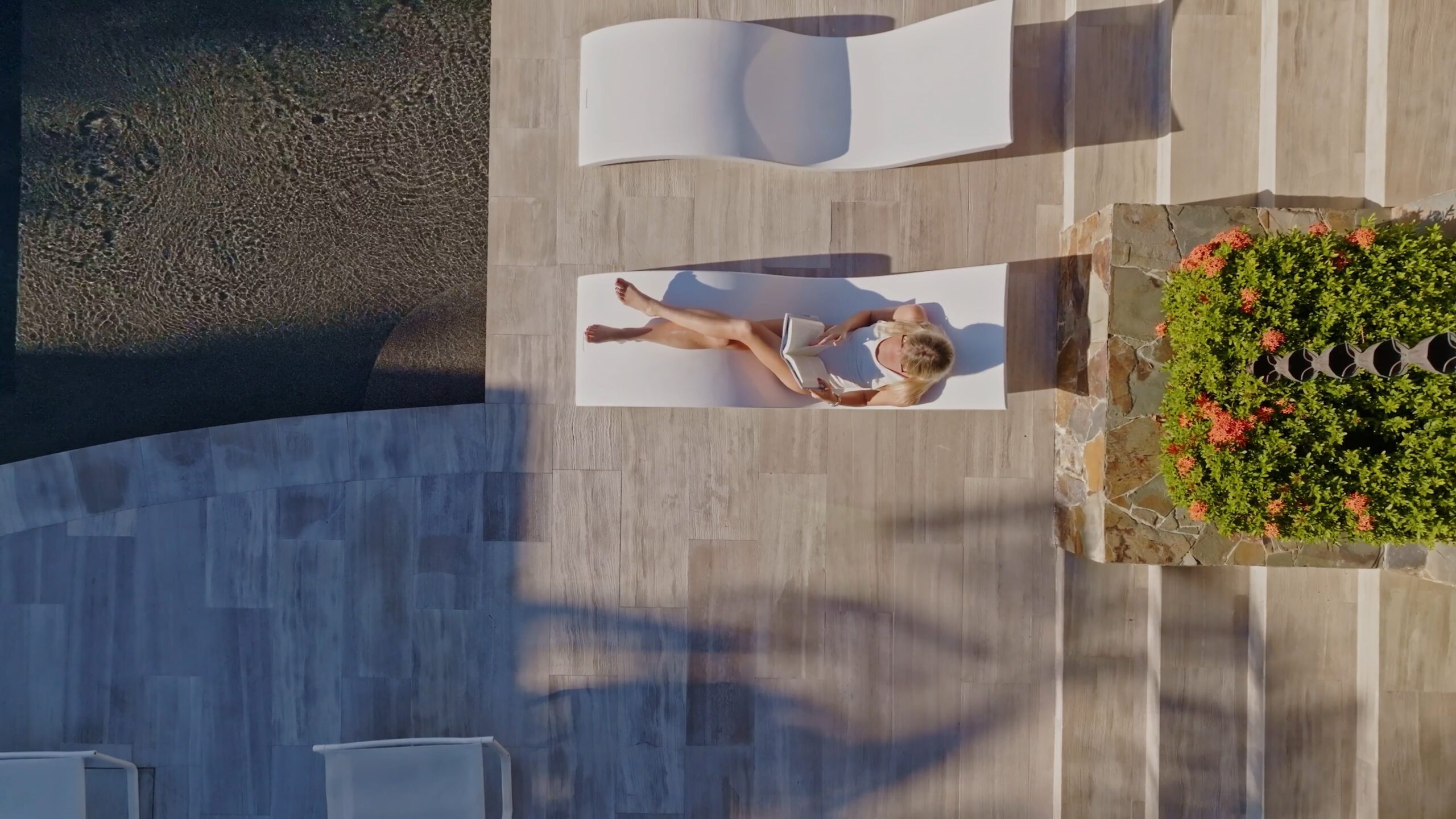 A woman lying on a deck chair, basking in the luxury of a stunning villa.